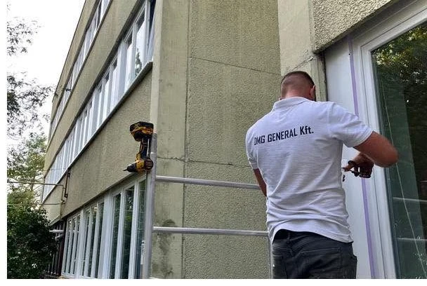 A DMG munkatársa társasházi ablaknál dolgozik