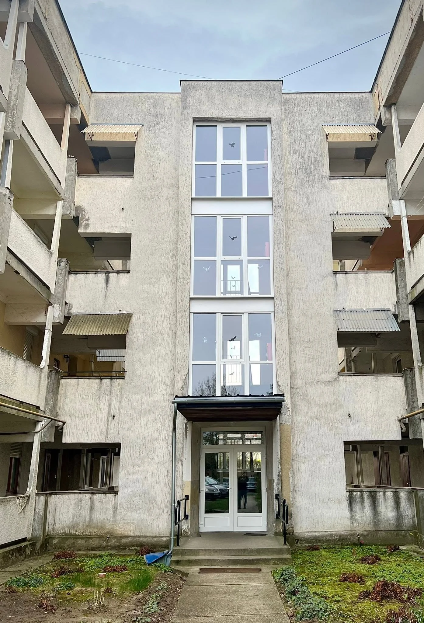 Társasházi lépcsőház fehér nyílászárókkal